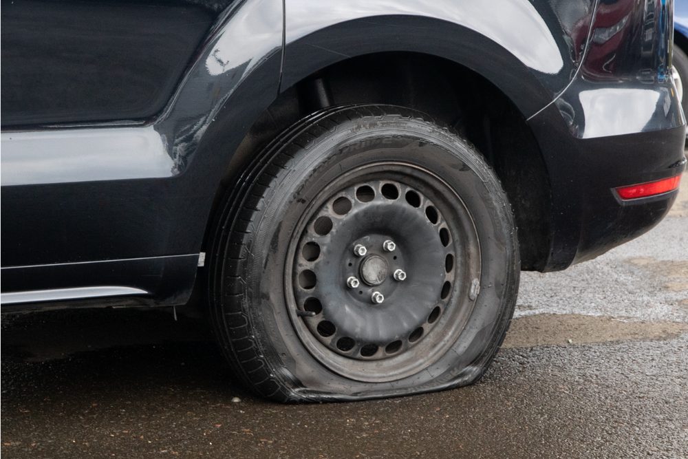 Flat car tyre on a parked vehicle.