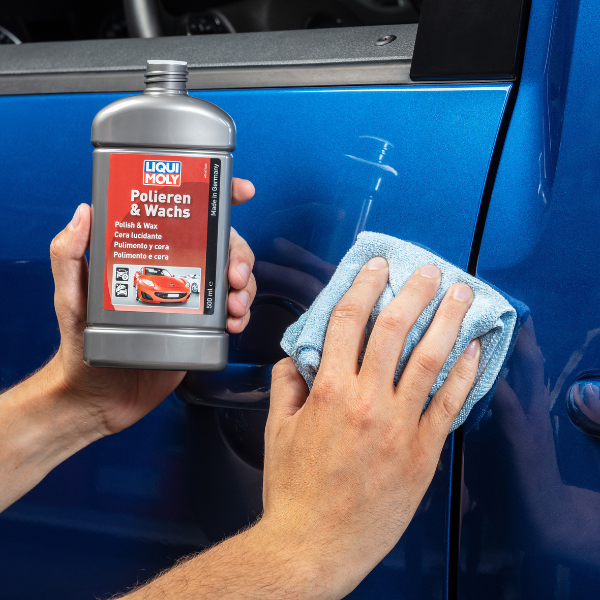 Person applying car polish to a blue car with a bottle of LIQUI MOLY Polieren & Wachs product.