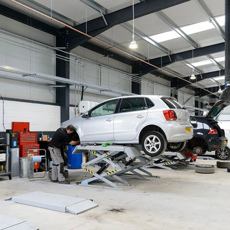 Automotive repair shop with cars on lifts and mechanics working.